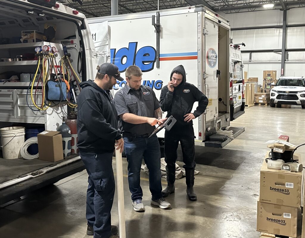 Three Wade Heating & Cooling team members going through a checklist together